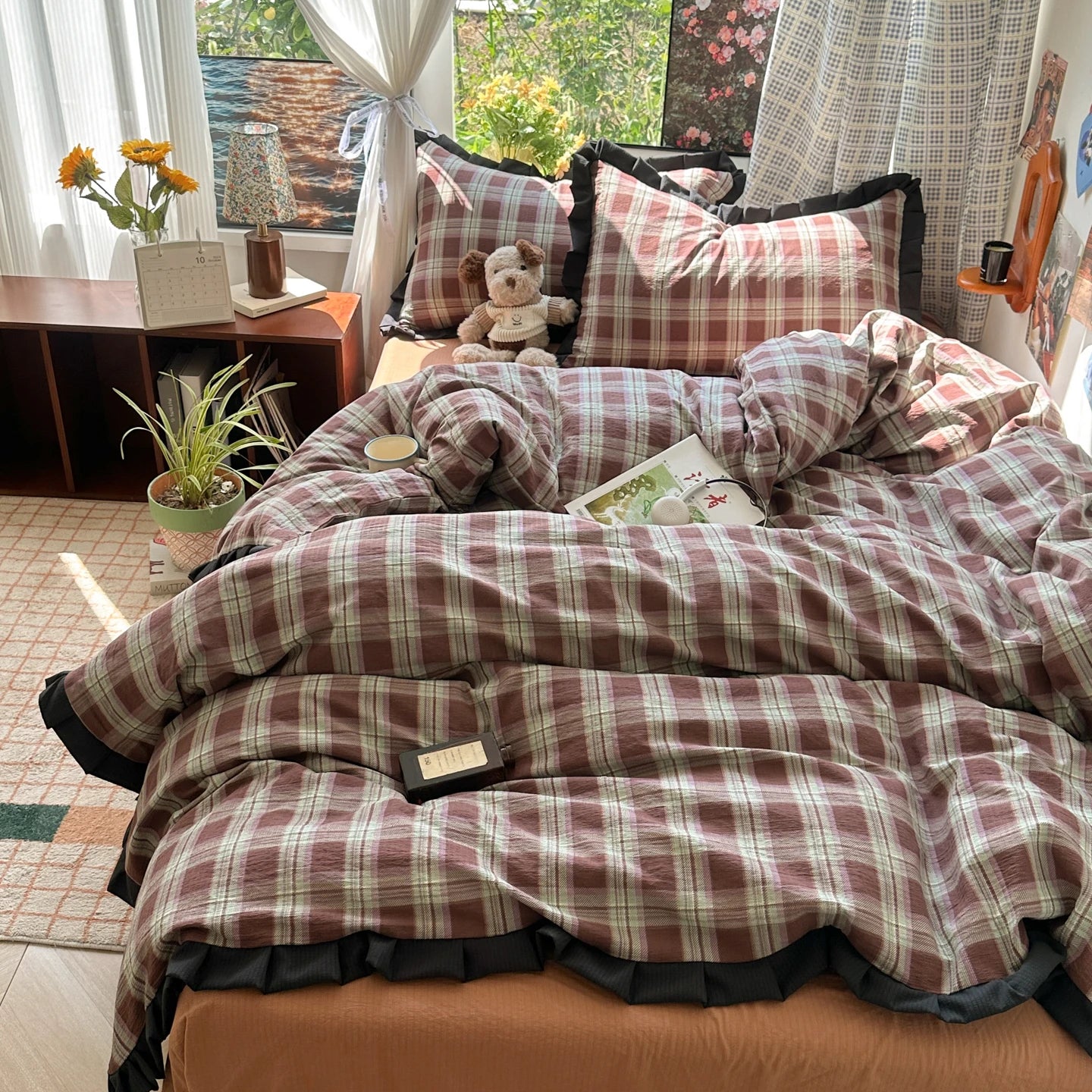 Bed with plaid comforter in a room with curtains and plants