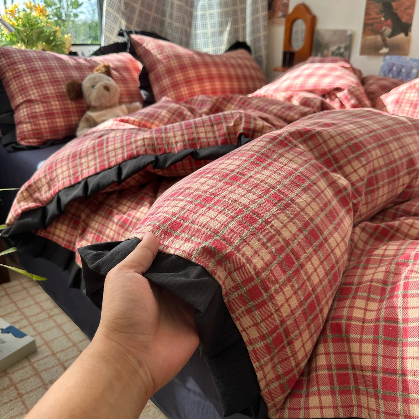 Red and beige checkered blanket draped over a chair with a hand holding it, in a room setting.