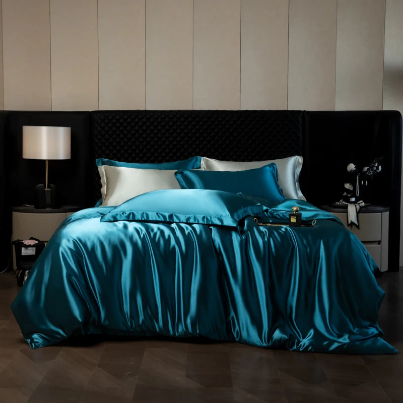 Teal satin bedding set on a bed with a dark headboard and nightstands.